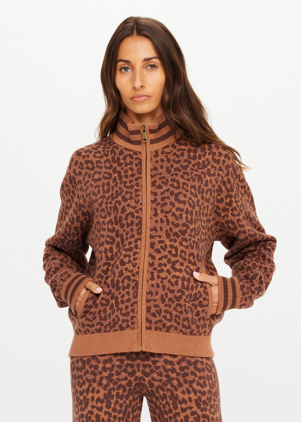 Woman wears a leopard print knit jacket, hands in pockets, standing forward. Suitable for casual or cool-weather wear.