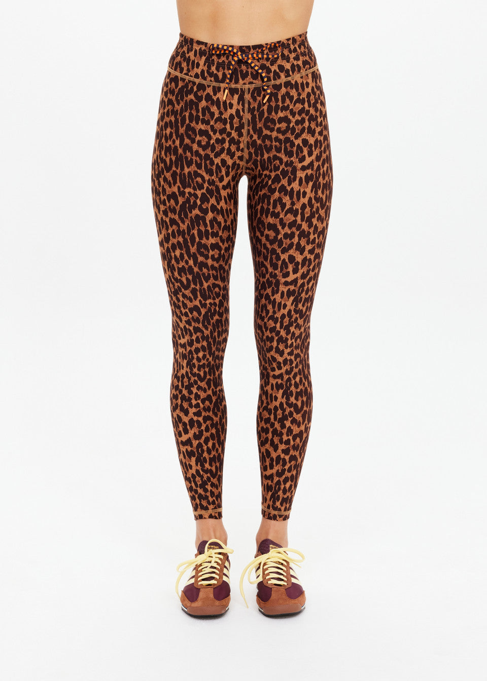 Leopard-print midi leggings paired with brown sneakers featuring yellow laces, shown against a white background.
