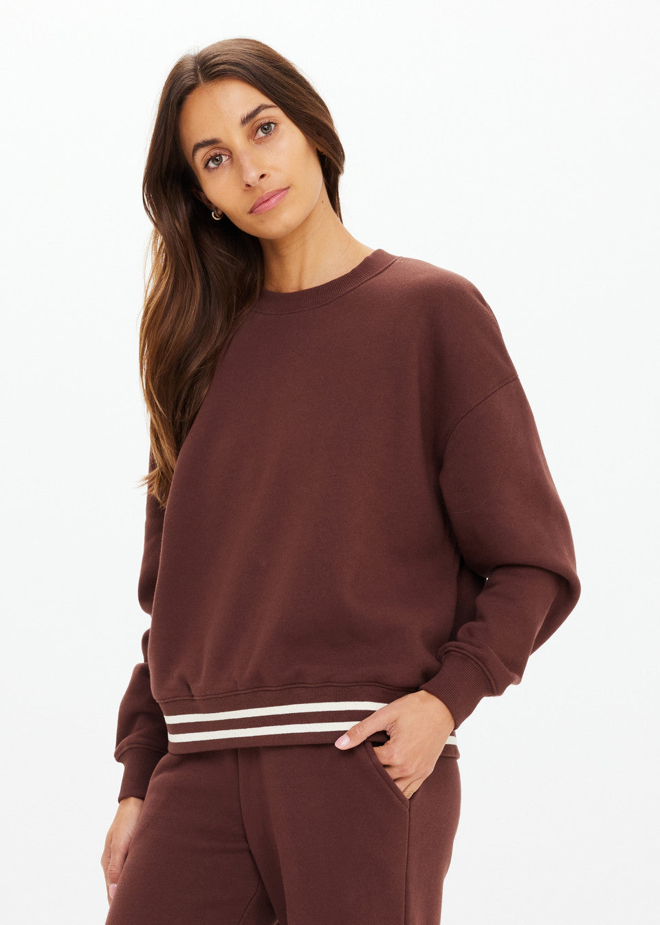 Woman in a cocoa crew neck sweater with white stripes, casual fit, soft material, standing against a plain white background.