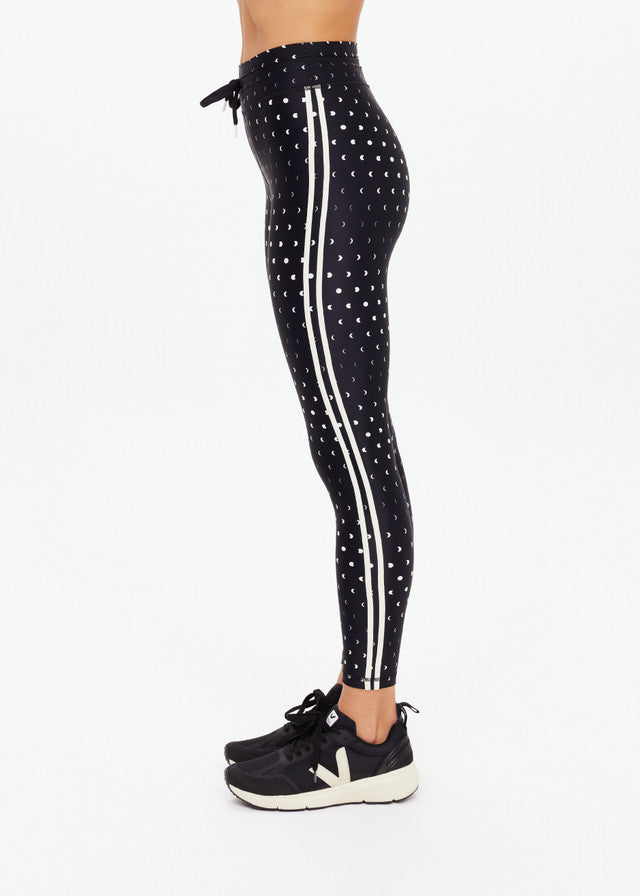Wearing black recycled-fabric midi leggings and black sneakers, suitable for athletic or casual wear.