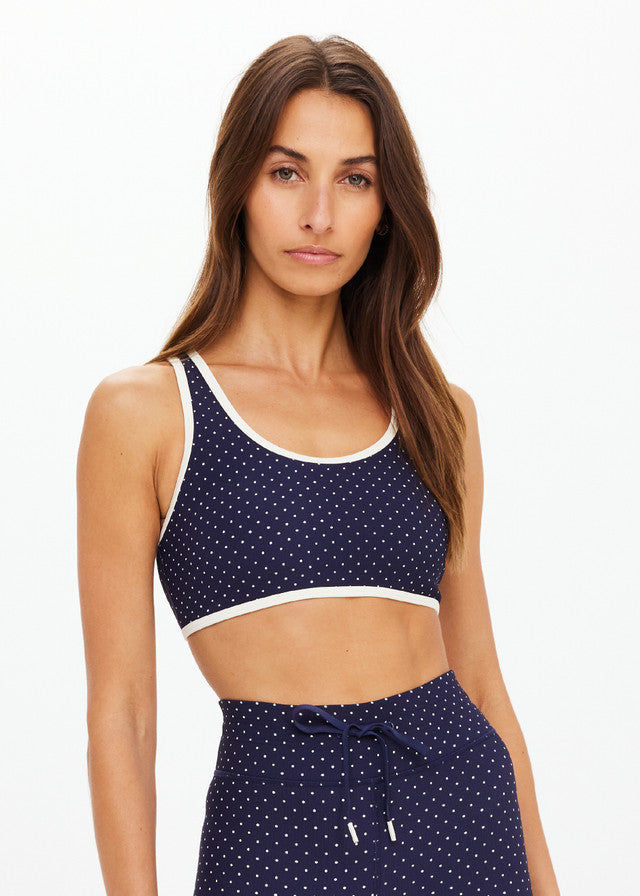 Jade polka dot racerback sports bra shown on a woman against a plain white background, suitable for activewear.