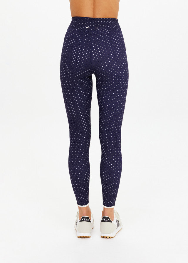 Back of black polka dot midi leggings paired with white sneakers, suitable for casual or athletic wear.