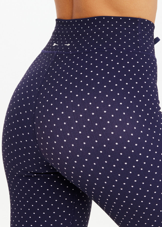 Person wearing navy blue midi pants with white polka dots, designed for active or casual use.