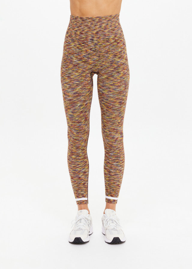 Model wears seamless, 25-inch daisy-print leggings and white sneakers, standing against a plain white background.