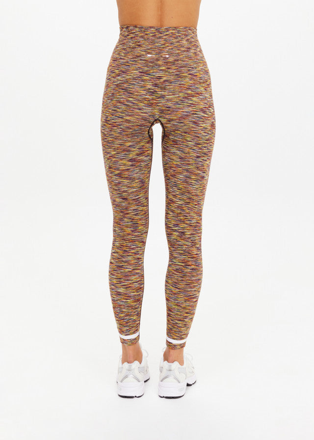 Back view of seamless 25in daisy-print midi leggings in soft fabric, paired with white sneakers on plain background.