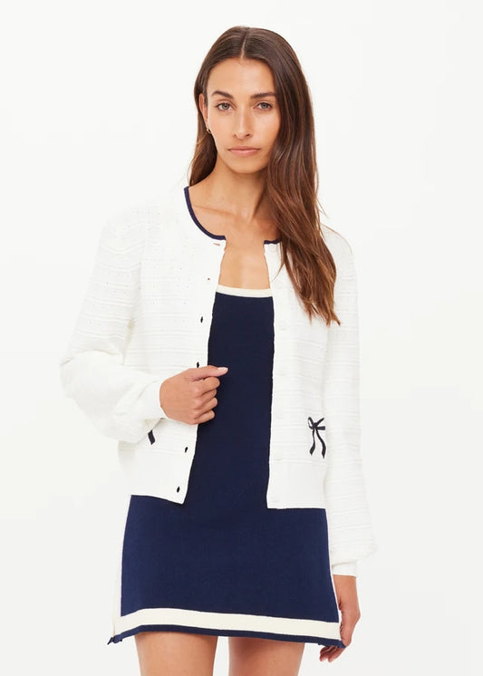 Woman wearing a white cardigan with black bow details