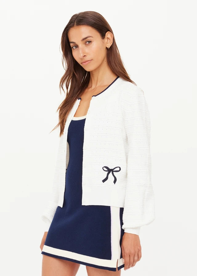 Woman wearing a white cardigan with black bow details
