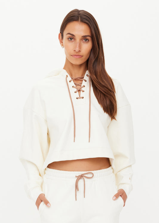 Cream cotton hoodie and matching sweatpants set on woman, shown against plain white background.