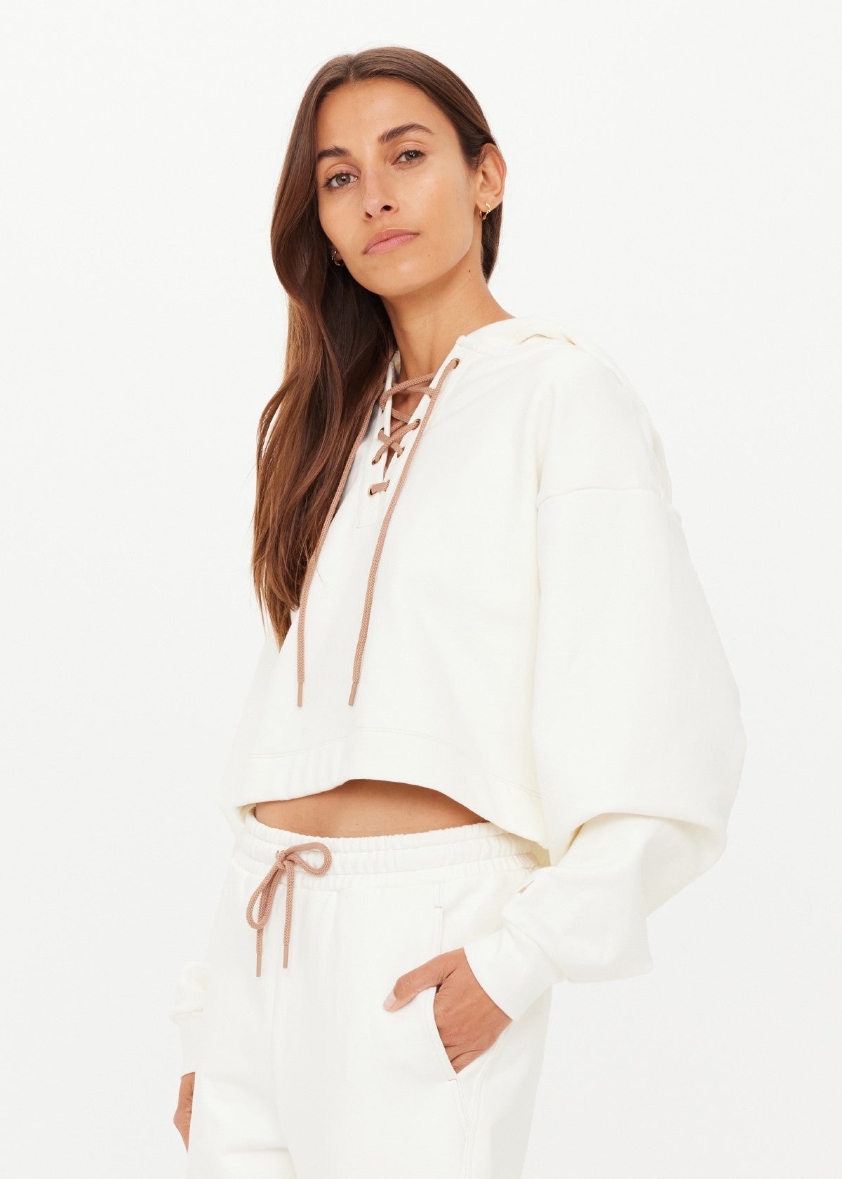 Woman in a cream cotton hoodie, relaxed pose with one hand in her pocket. Suitable for casual wear.