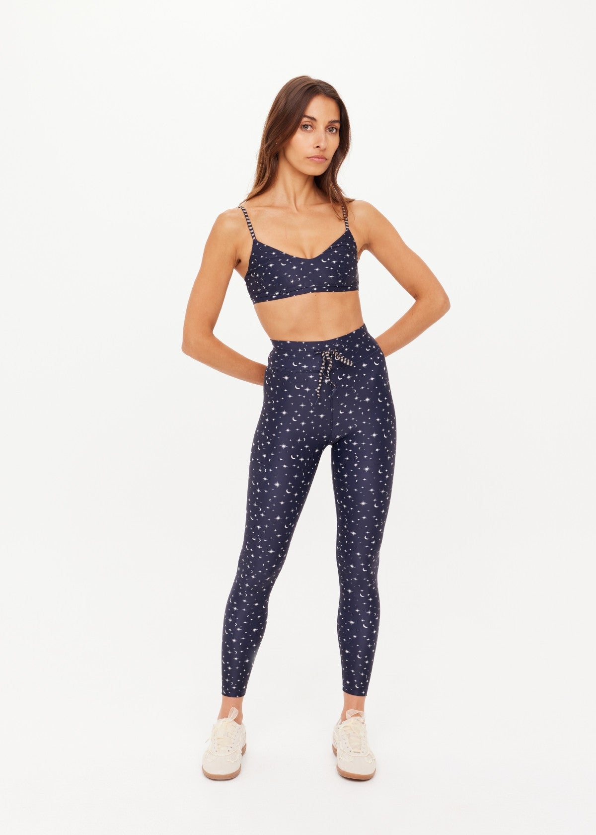 A woman modeling a navy blue two-piece lounge set with a white celestial print of stars and crescent moons
