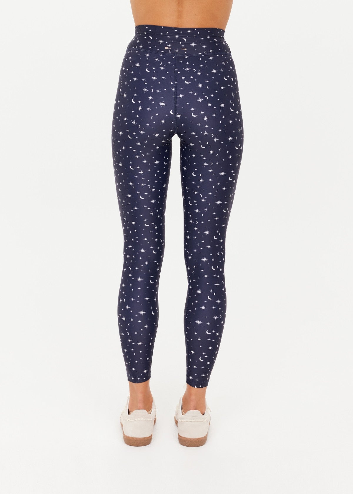A woman wearing navy leggings with a white star and moon print