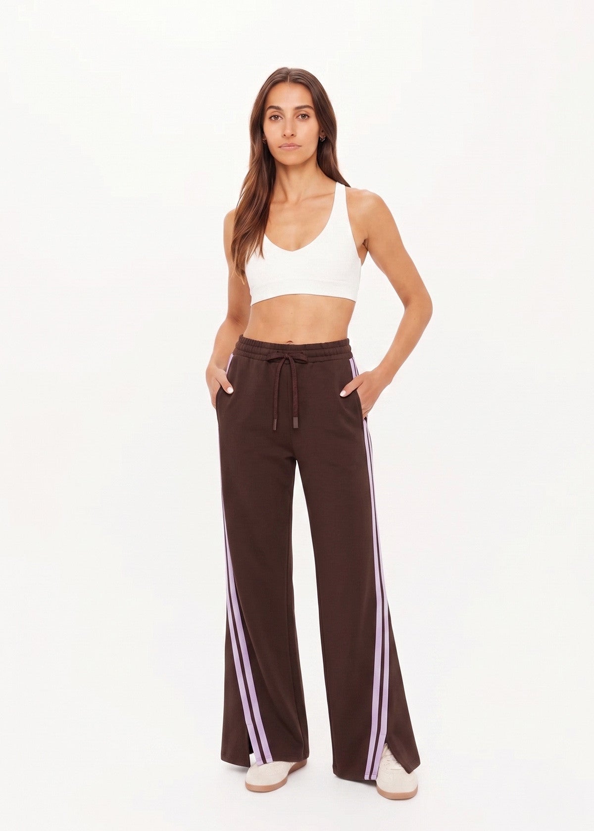 Woman wears cocoa brown Roma pants, hands in pockets, showing the fit and style of the garment in a casual setting.