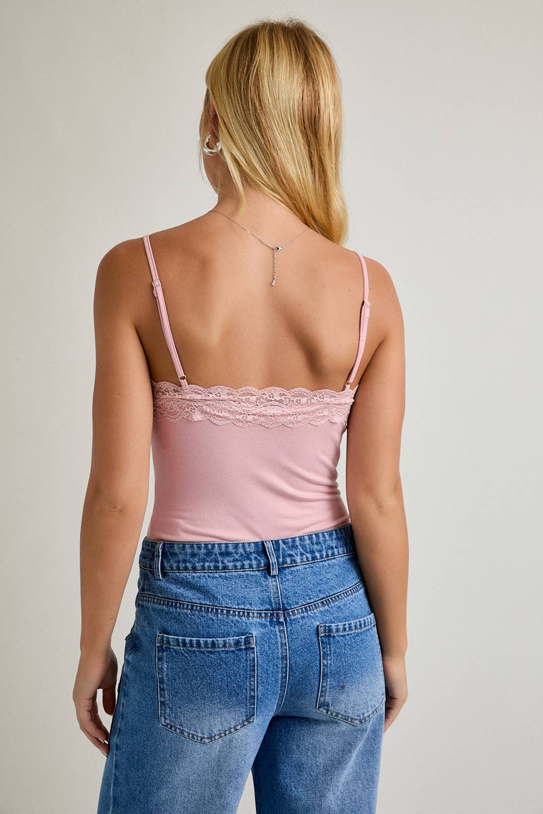 Back view of woman in dusty pink bodysuit, size small, long blonde hair visible.