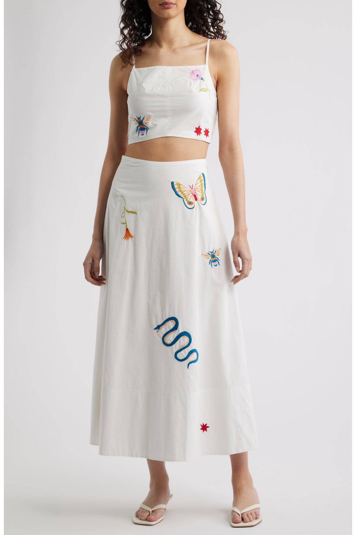 Woman in a white skirt and matching top with colorful embroidery