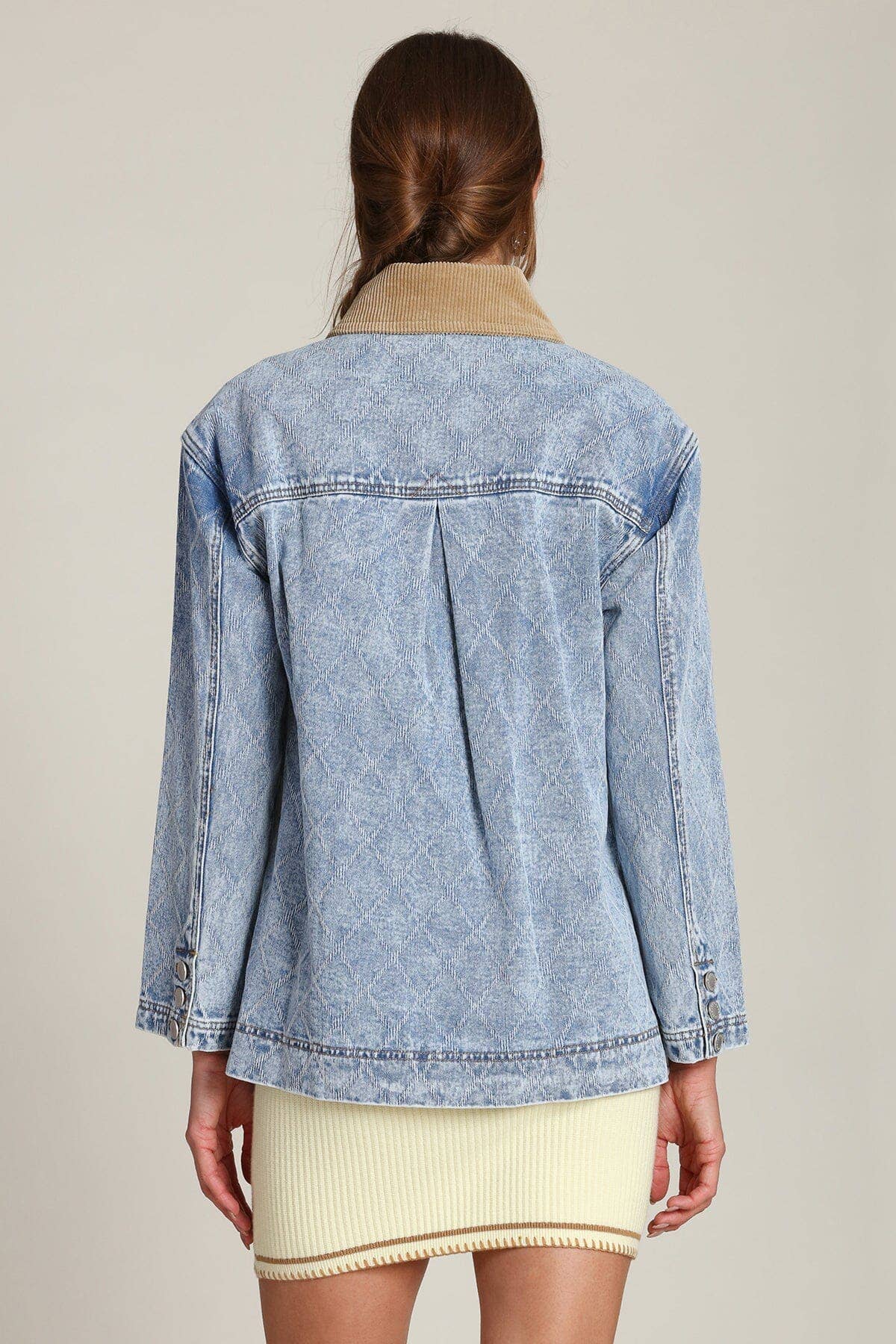 Back view of a woman with long brown hair wearing a blue denim barn jacket made from sturdy cotton material.