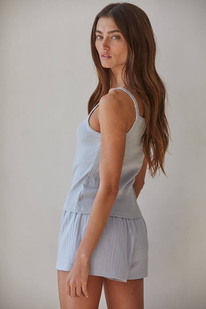 Woman in a neutral-toned cami and matching shorts set, made of lightweight fabric, standing in profile.