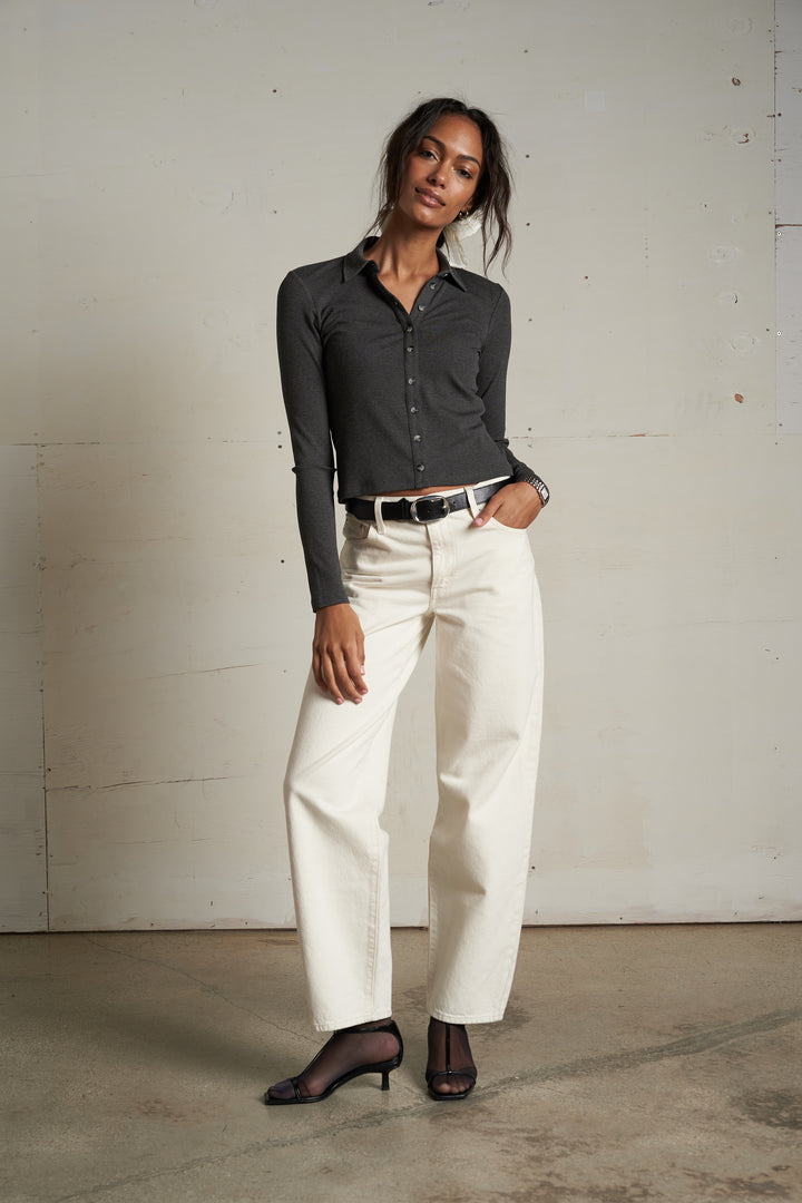 Charcoal button-up shirt, white wide-leg pants, and black heels worn by a light wall.