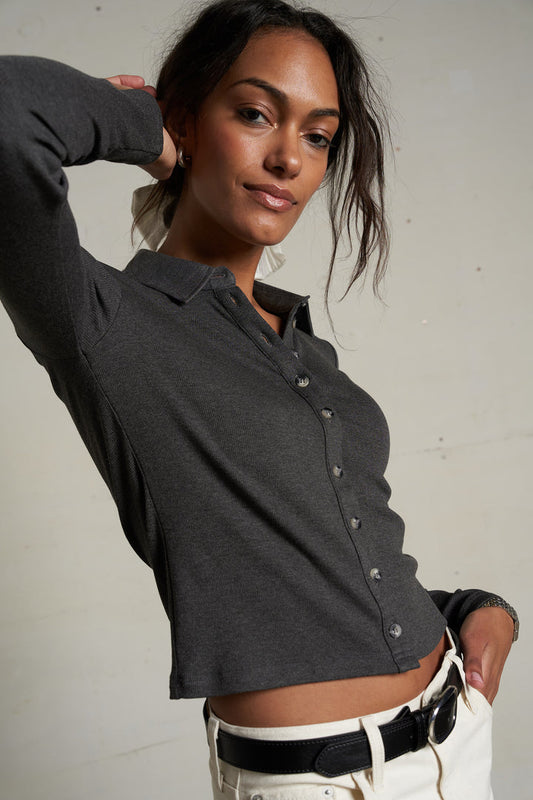 Woman models a charcoal button-up cotton top with white pants, suitable for casual or workwear.