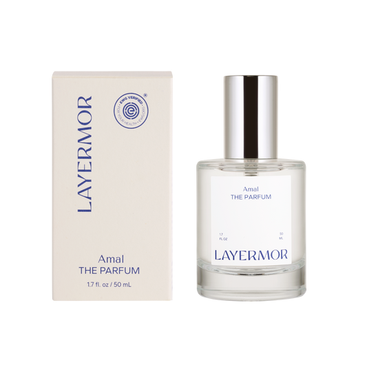 A clear perfume bottle with a silver cap beside its matching box, both labeled Layermor Amal, for personal fragrance use.