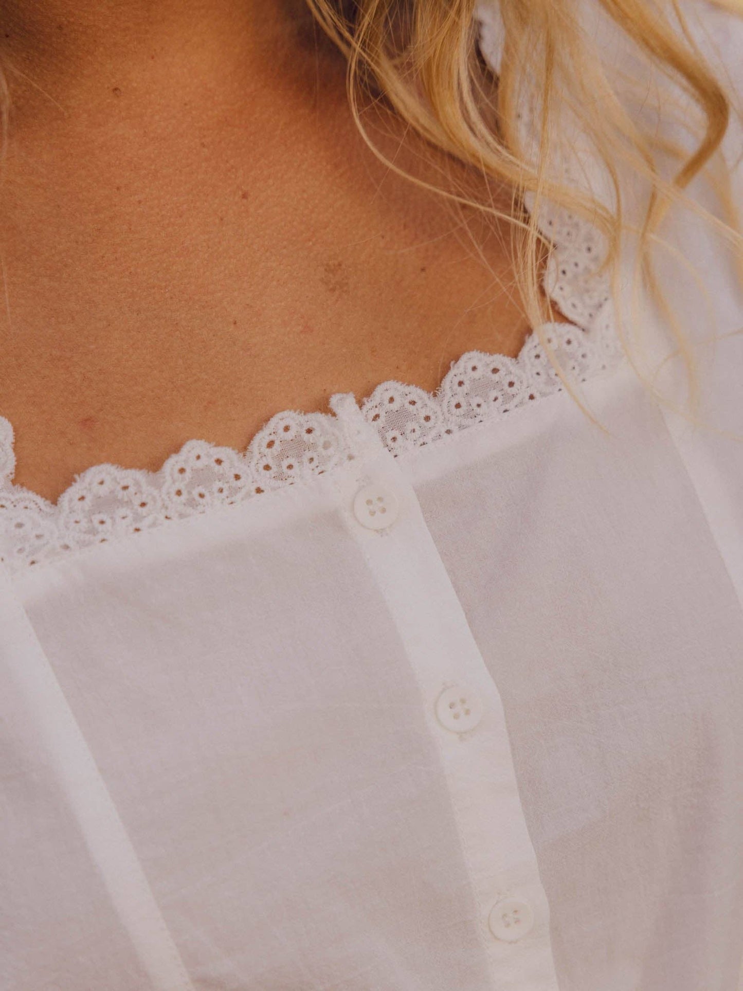White Victorian-style blouse with lace trim and front buttons, ideal for casual or semi-formal wear. Cotton blend material.