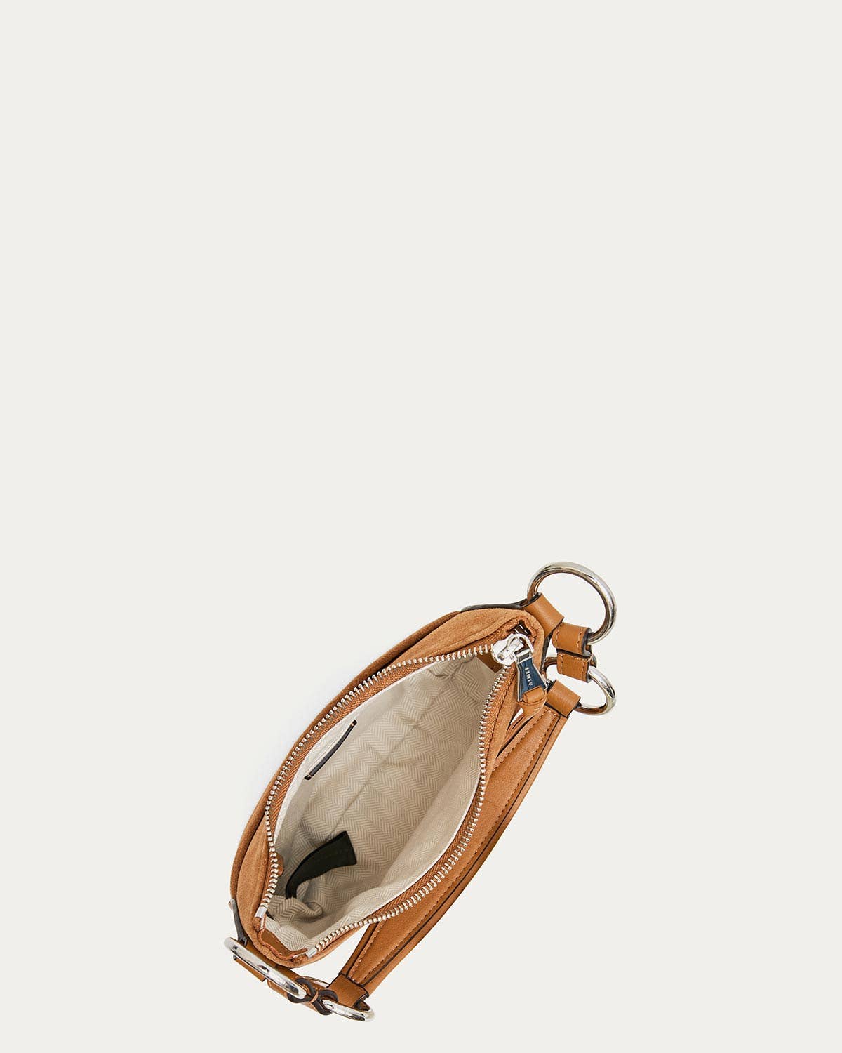 Latte suede mini crossbody bag with bold strap, silver zipper, beige lining, and a small interior pocket.