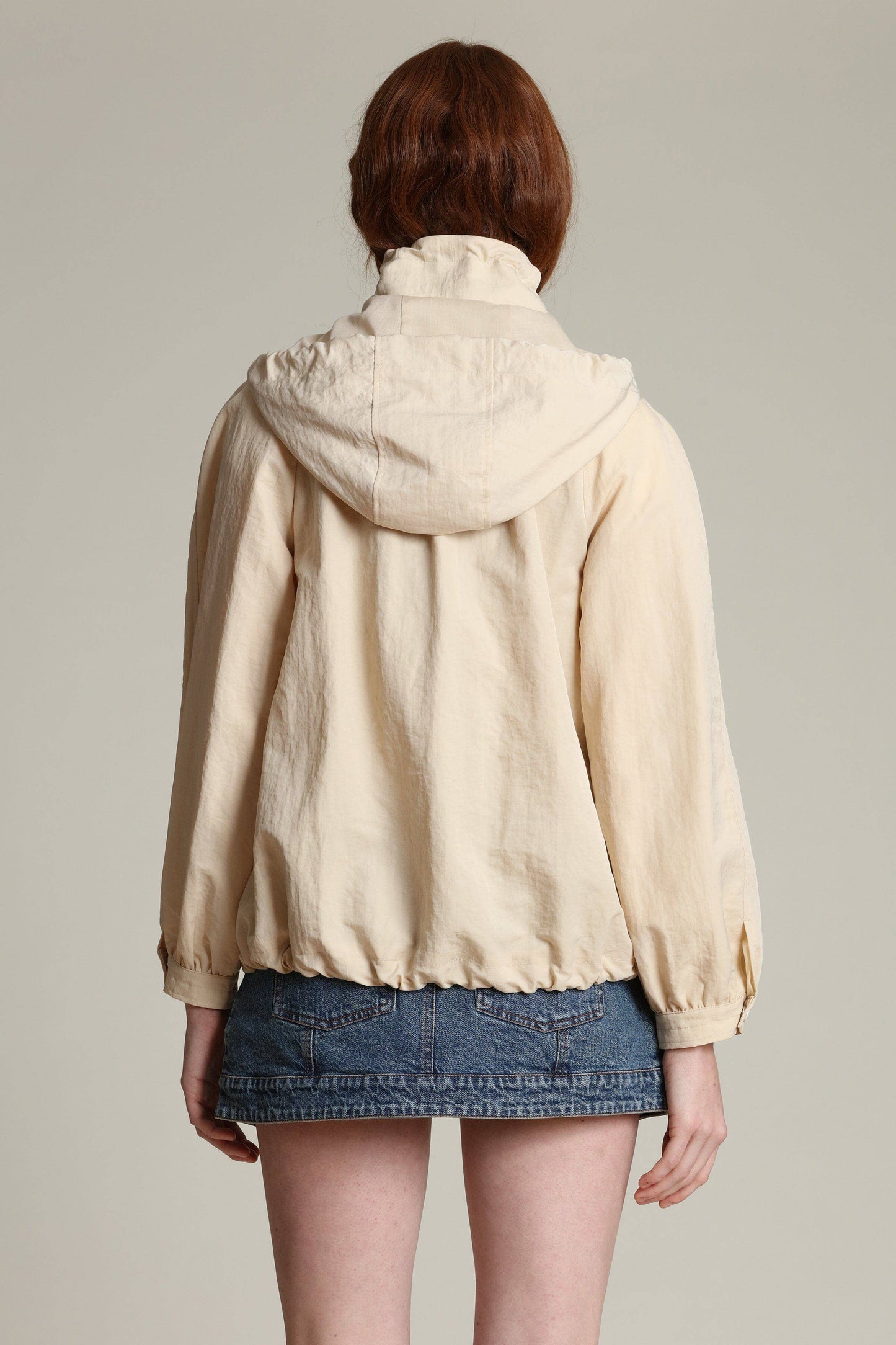 Back view of a balloon sleeve windbreaker and denim mini skirt in neutral tones, suitable for casual outdoor wear.