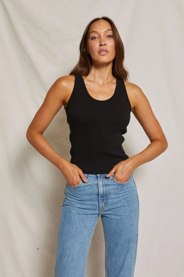 Woman wearing a black tank top and blue jeans 