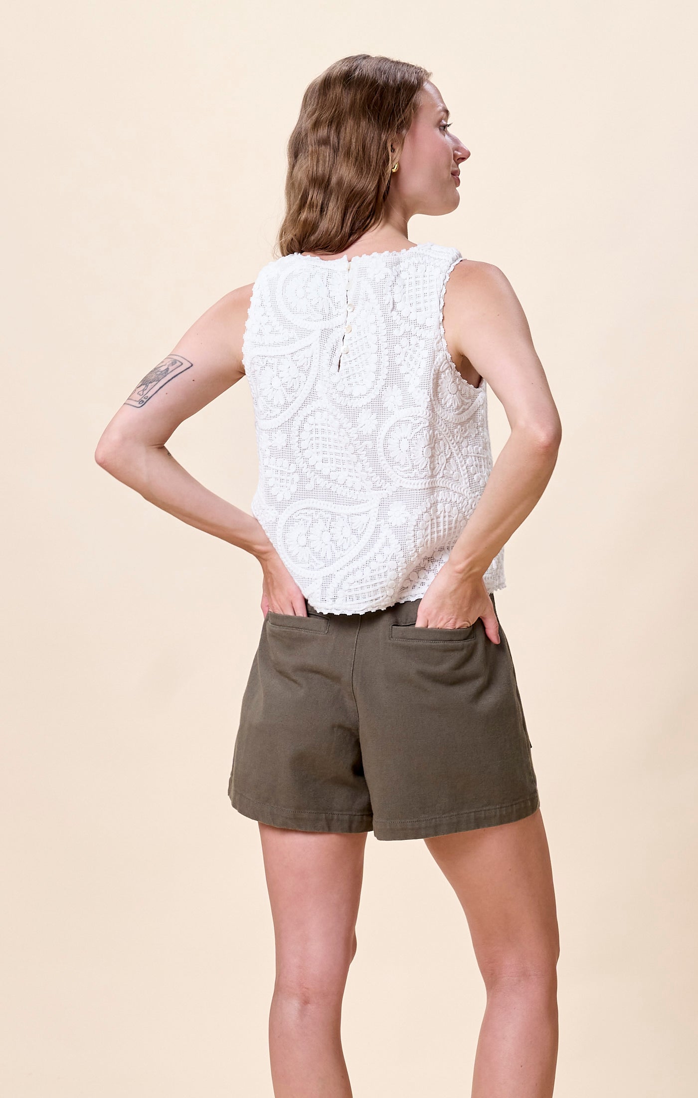 Woman wearing a white sleeveless embroidered top 