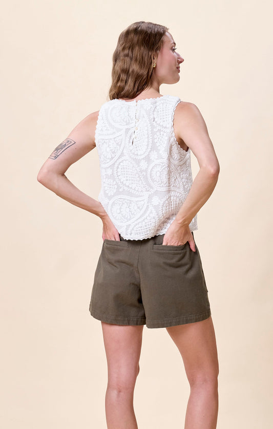 Woman wearing a white sleeveless embroidered top