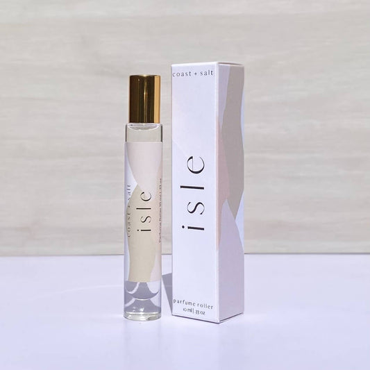 A clear glass perfume roller with a white cap sits beside a blue and cream abstract-patterned box.