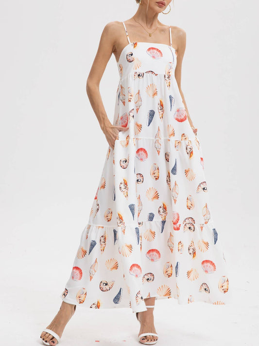 White maxi dress with colorful seashell print and spaghetti straps, made from lightweight fabric, suitable for warm weather.