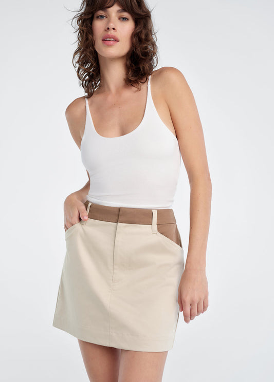 Woman wearing a white tank top and beige skirt