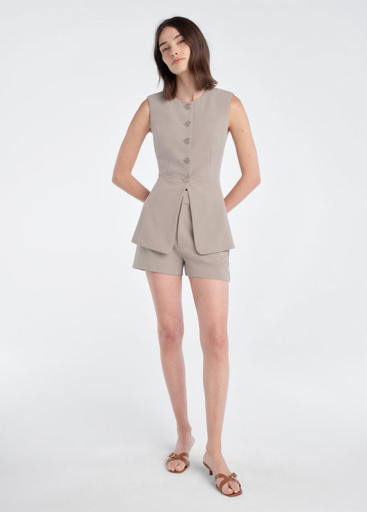 Woman in soft taupe mini shorts, sleeveless top, and brown sandals. Tailored cotton blend; ideal for warm weather casual wear.