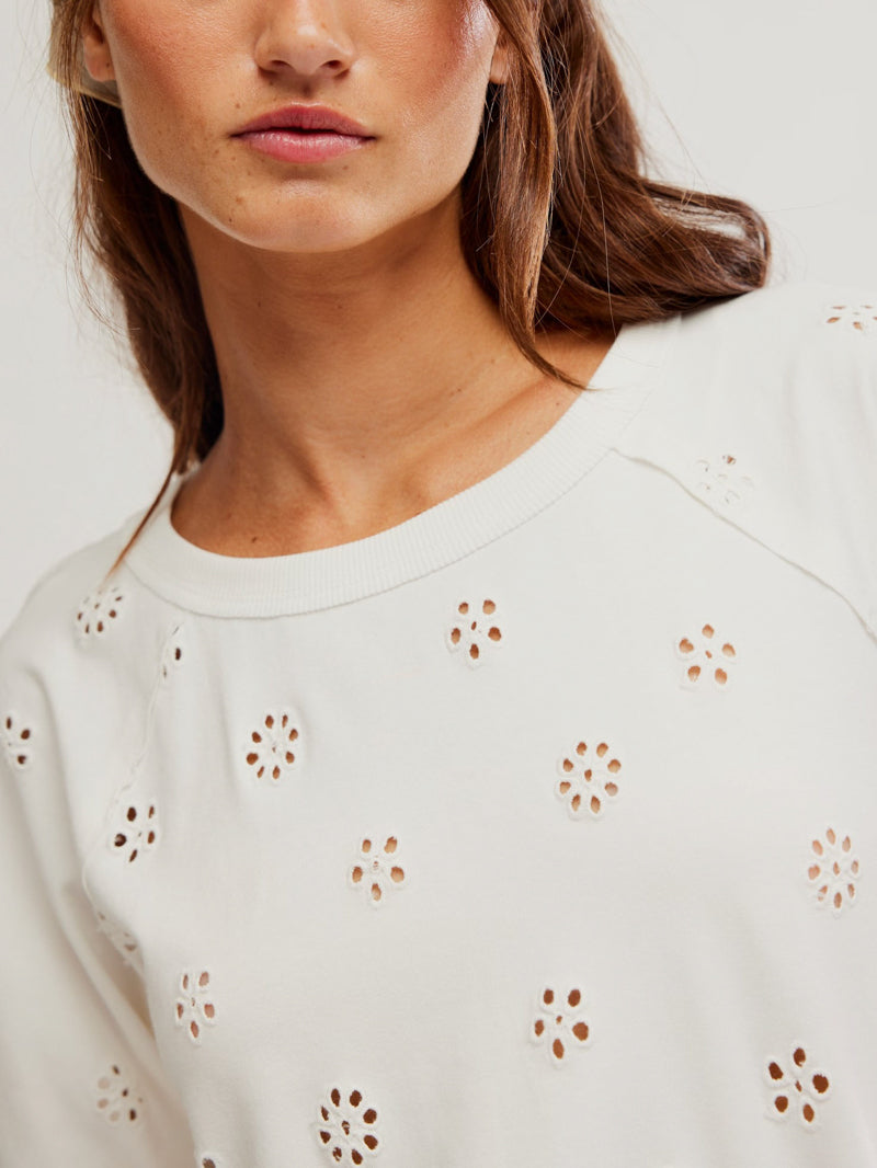 Close-up of a woman in a white eyelet cotton tee, ideal for casual or warm weather wear. Only shoulders up are visible.