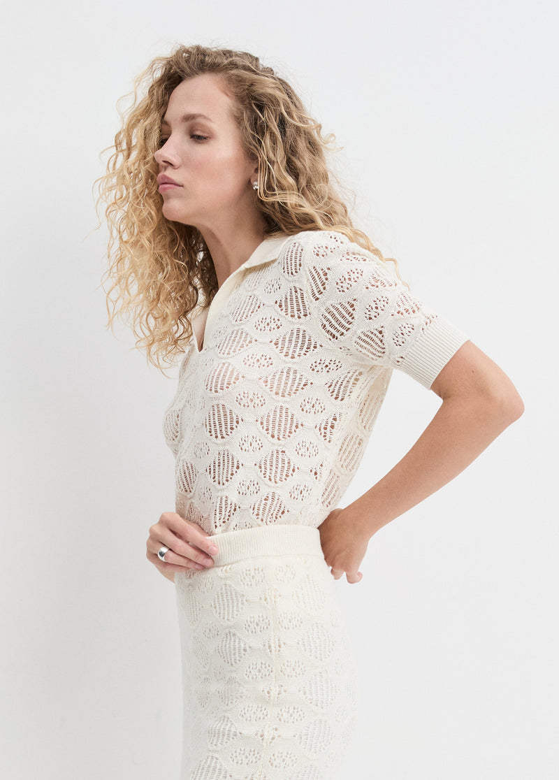 Woman in an ivory short-sleeve polo shirt, cotton blend, suitable for casual or semi-formal daytime wear.