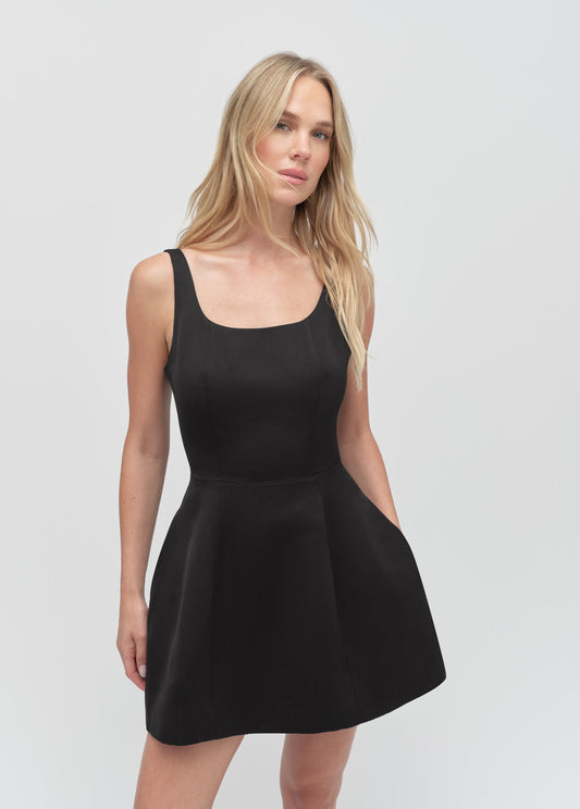 Sleeveless black mini dress with a scoop neck, shown on a model against a plain white background.