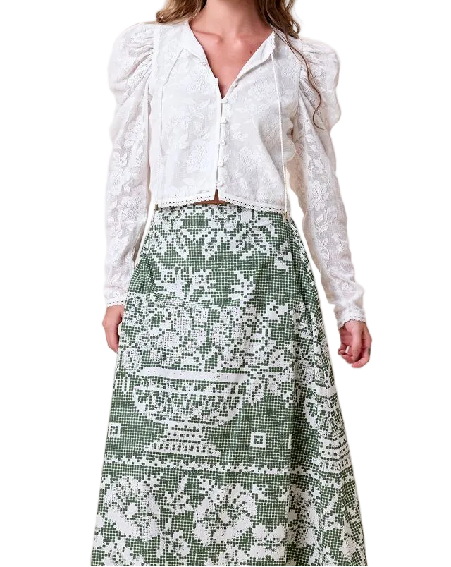 White blouse paired with a green skirt featuring a white floral and vase print, suitable for casual or semi-formal wear.