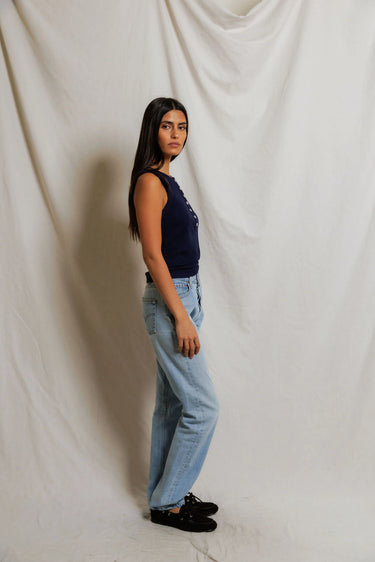 Woman in a navy sleeveless top with buttons