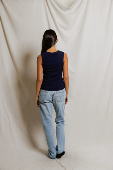Woman in a navy sleeveless top with buttons