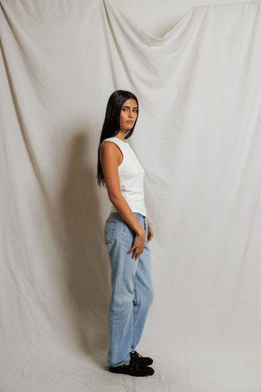 Woman wearing a white sleeveless top with buttons