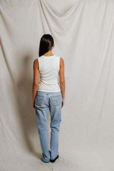 Woman wearing a white sleeveless top with buttons