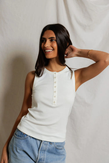 Woman wearing a white sleeveless top with buttons