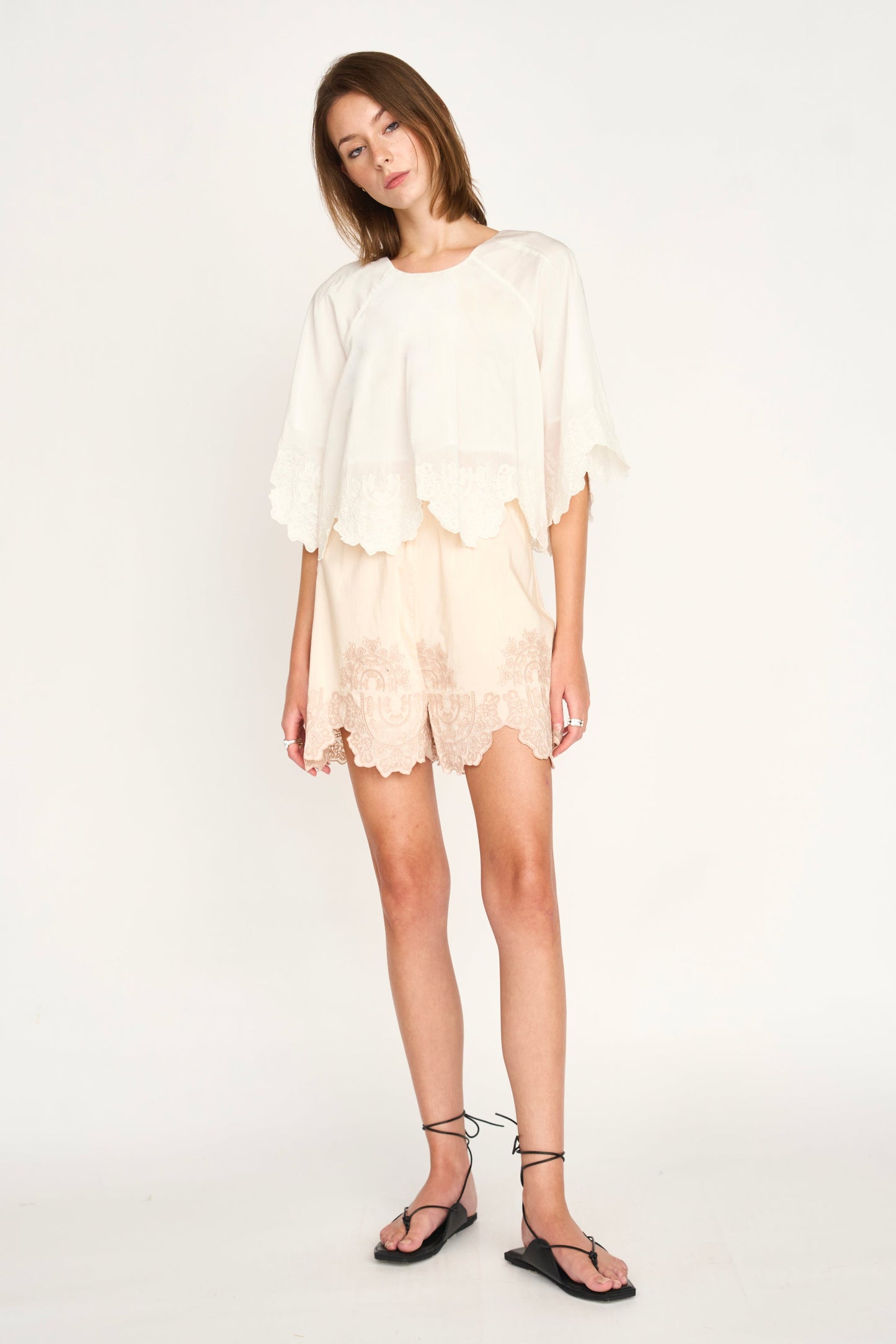 White eyelet Bari top, short sleeves, worn by woman standing against a plain white background; casual cotton summer wear.