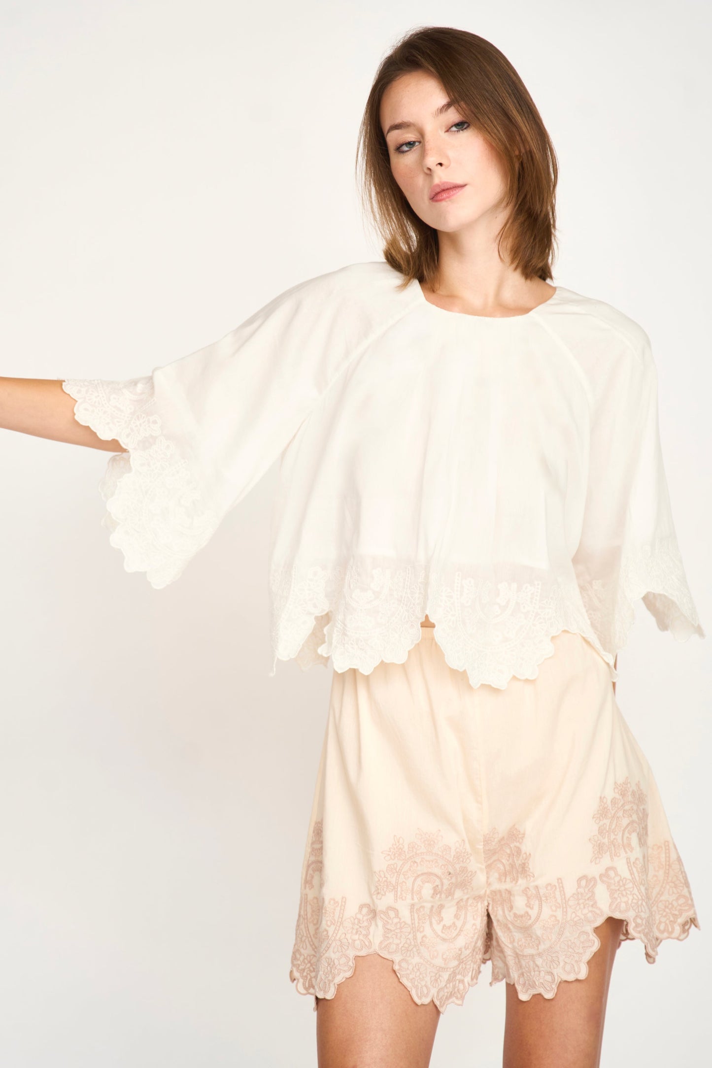 White eyelet-embroidered top and light shorts set made of cotton, shown on a plain background. Ideal for warm weather wear.