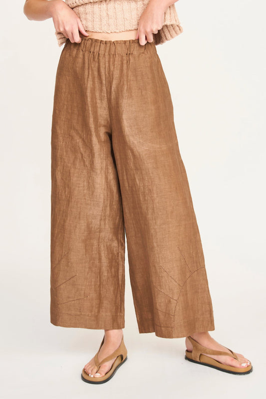 Brown cotton Mirth pants with a cropped knit top and sandals, modeled against a plain backdrop, suitable for casual wear.
