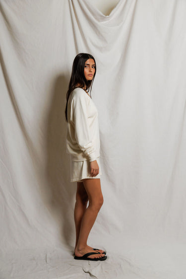 Woman wearing an ivory v-neck sweater and sweat shorts