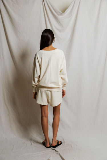 Woman wearing an ivory v-neck sweater and sweat shorts