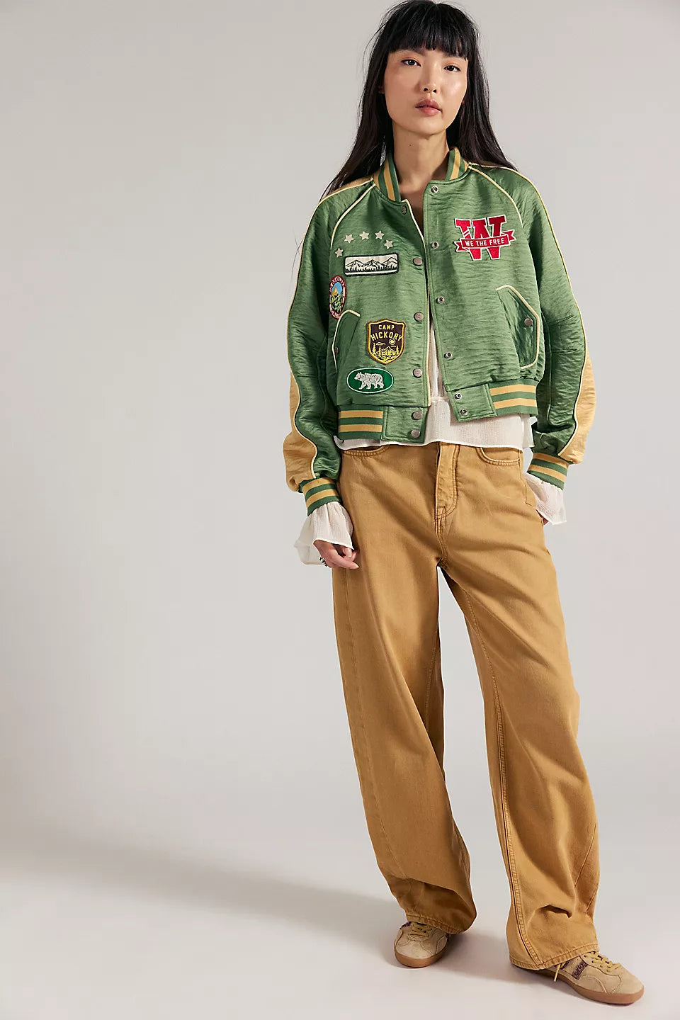 Woman in vintage green souvenir jacket, wide-leg tan pants, and tan sneakers. Casual outerwear suitable for cool weather.