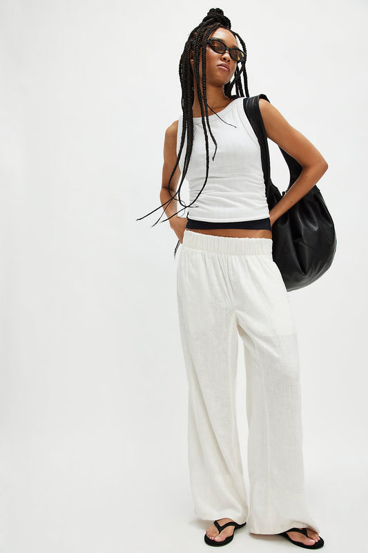 Woman in white tank top and ivory linen pull-on pants, wearing sunglasses and black sandals.