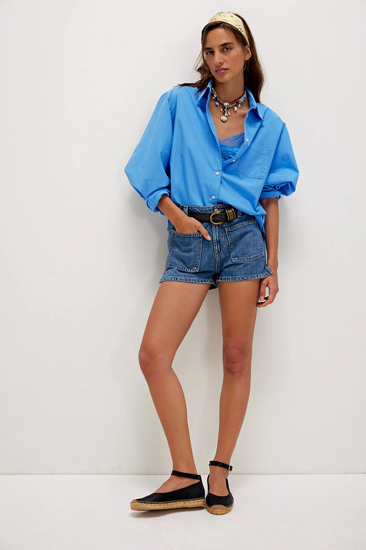 Woman in blue shirt, lace camisole, black denim shorts, black espadrilles, and necklace.